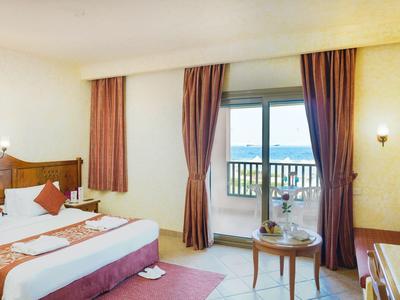 Helles Doppelzimmer mit Balkon, Blick auf das Meer und Holzmöbeln.