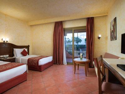 Habitación de hotel con dos camas individuales, balcón y vista al exterior.