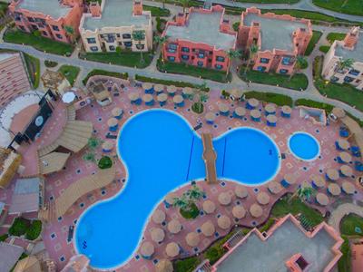 Drei blaue Swimmingpools umgeben von Sonnenschirmen und einem Hotelkomplex, aufgenommen aus der Vogelperspektive.