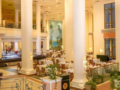 Elegantes Hotelrestaurant mit weißen Säulen, gedeckten Tischen und warmem Licht.