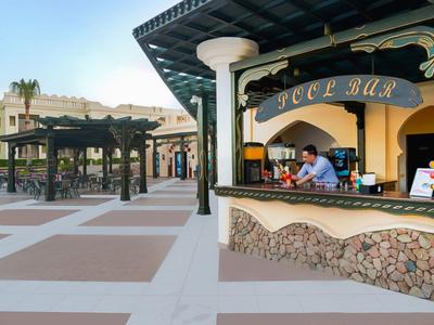 Moderner Außen-Cocktailbarbereich mit offenem Tresen und Tischen unter Pergola an einem Hotel.