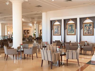 Área de comedor moderna en hotel con sillas cómodas y cuadros decorativos en paredes blancas.