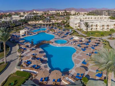 Gran piscina de hotel con sombrillas y tumbonas en un resort tropical.