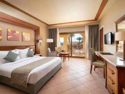 Habitación de hotel luminosa con cama doble, muebles de madera y balcón con vista al mar.