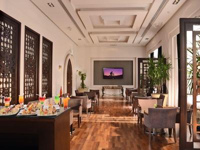 Elegante área de salón de hotel con suelos de madera, sillones cómodos y separadores decorativos.