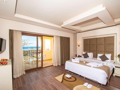 Helles Hotelzimmer mit Doppelbett, Balkon und Meerblick.
