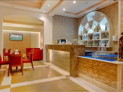 Heller Hotel-Lobbybereich mit Bar, roten Stühlen und moderner Beleuchtung.