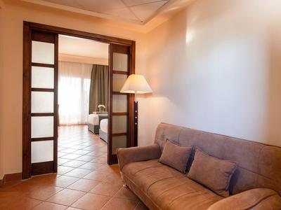 Gemütliches Wohnzimmer mit braunem Sofa und Blick auf angrenzenden Raum durch Glastür.