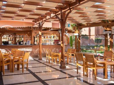 Hell beleuchtete Terrasse mit Holzstühlen und Tischen neben einer Bar in einem Hotel.