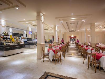 Eleganter Hotelrestaurantbereich mit weißen Säulen, gedeckten Tischen und Buffetstation.