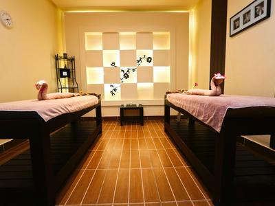 Spazio für Massage mit zwei Liegen, warm beleuchtet und dekorativ gestaltet.