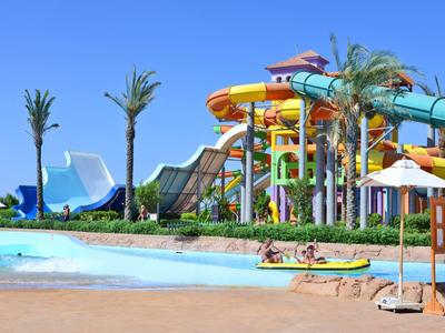 Wasserpark mit Rutschen, Pool und Palmen unter klarem blauem Himmel.