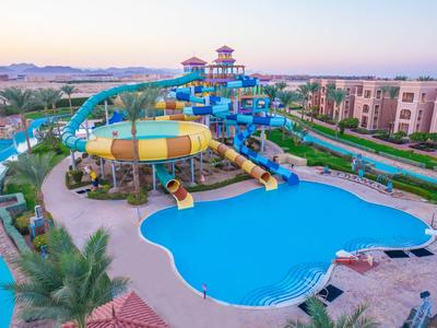 Großer Wasserpark mit Rutschen und Pool in einem Hotelresort bei Sonnenuntergang.