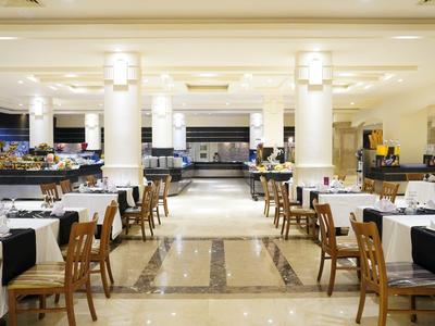 Elegantes Restaurant mit weißen Tischdecken und Holzstühlen in modernem Hotel.