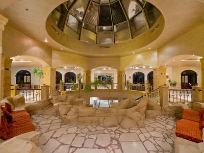Intérieur d'hôtel avec piscine ronde, fauteuils rouges et plafond en verre.