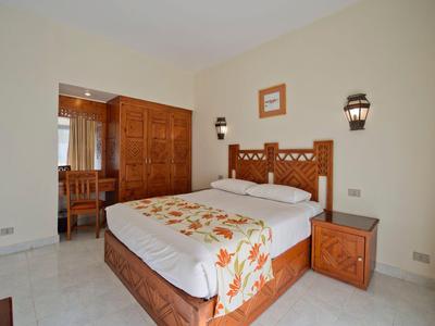 Chambre d'hôtel lumineuse avec mobilier en bois, lit double et éclairage indirect.