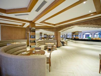 Salon d'hôtel spacieux avec canapés courbés et accents en bois sous un éclairage chaleureux.