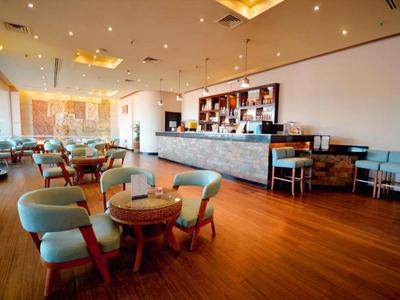 Helles Hotelrestaurant mit Holzboden, runden Tischen und mintgrünen Stühlen.