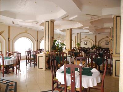 Helles Hotelrestaurant mit runden Tischen und dekorativen Bögen an den Wänden.