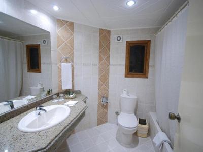 Modernes Badezimmer mit Waschtisch, Toilette und zwei kleinen Fenstern in einem Hotelzimmer.
