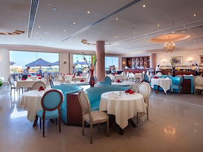 Salle de restaurant d'hôtel lumineuse et spacieuse avec tables dressées et vue sur la terrasse.