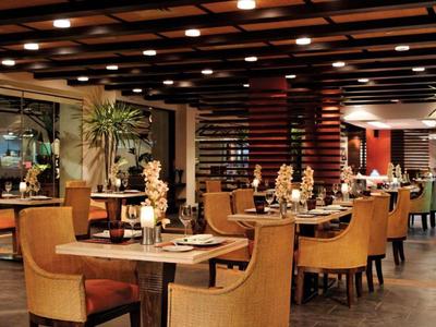 Modern eingerichtetes Hotelrestaurant mit Holztischen, bequemen Stühlen und warmem Licht.