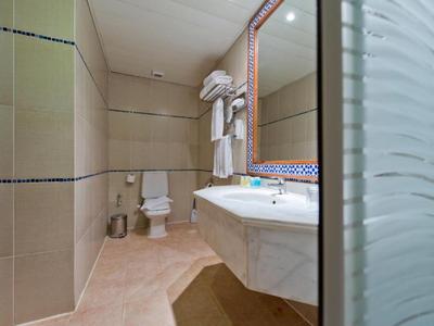 Sauberes Hotelbadezimmer mit weißem Waschbecken, Toilette und Handtüchern an der Wand.