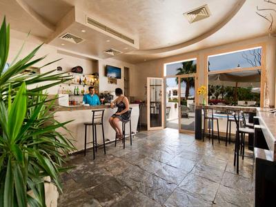 Hell gestaltete Hotelbar mit Sitzgelegenheiten, Pflanzen und offenem Zugang zur Terrasse.