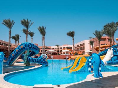 Grand piscine d'hôtel avec toboggans bleus et palmiers sous un ciel clair.