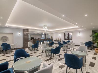 Eleganter Hotel-Speisesaal mit weißen Wänden, grauen und blauen Stühlen und Marmorfußboden.
