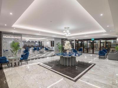 Moderner Empfangsbereich mit Marmorfliesen, blauen Sesseln und stilvoller Beleuchtung in einem Hotel.