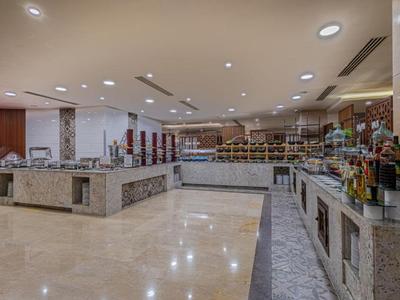 Großer Hotel-Speisesaal mit Buffetbereich, Marmor- und Holzdetails sowie heller Beleuchtung.