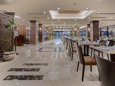 Weitläufiger, moderner Hotelrestaurantbereich mit glänzendem Marmorboden und stilvollen Sitzgelegenheiten.
