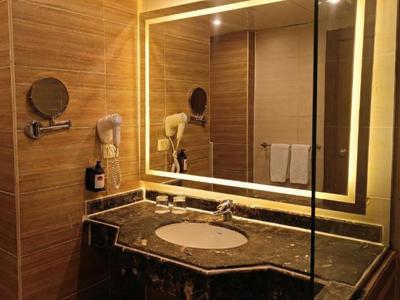 Modernes Hotelbadezimmer mit beleuchtetem Spiegel und Marmorwaschbecken.