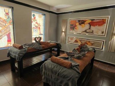 Zimmer mit zwei Massageliegen, warmen Tönen und künstlerischen Wanddekorationen im Wellnessbereich.