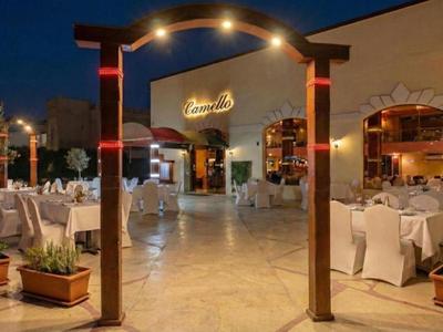 Abendliche Hotelterrasse mit gedeckten Tischen, Beleuchtung und Pflanzen im Außenbereich.