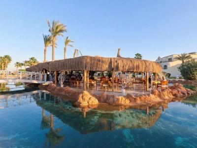 Pool mit tropischer Bar auf einer Insel und Palmen im Urlaubshotel.