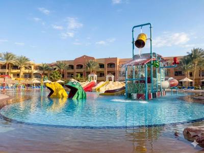 Ein großer Hotelpool mit Wasserrutschen, Spielgeräten und umliegenden Gebäuden bei sonnigem Himmel.