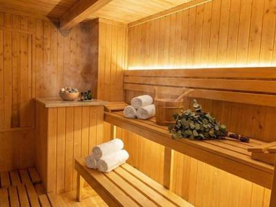 Ein Holzzaun mit Holzbänken, Handtüchern und Saunaaufguss-Zubehör in einer Sauna.