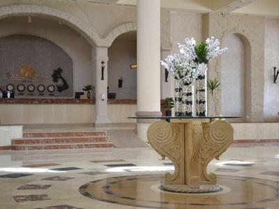 Großer Hotellobby mit Marmorboden, Säulen und Blumendekoration in zentralem Bereich.