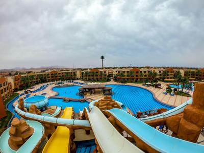 Großer, verspielter Außenpool mit Rutschen und umliegenden Hotelgebäuden bei bewölktem Himmel.