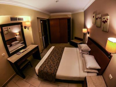 Gemütliches Hotelzimmer mit Doppelbett, Schreibtisch, Stuhl und warmem Lichtambiente.