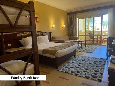 Hell eingerichtetes Hotelzimmer mit Familienstockbett, Doppelbett und Balkon mit Aussicht.