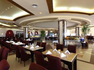 Moderner Hotelrestaurantbereich mit gedeckten Tischen und eleganter Beleuchtung.