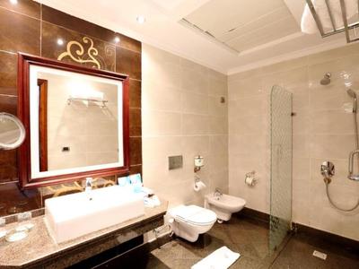 Moderner Hotelbadezimmer mit weißem Waschbecken, Toilette, Bidet und großer Spiegelwand.