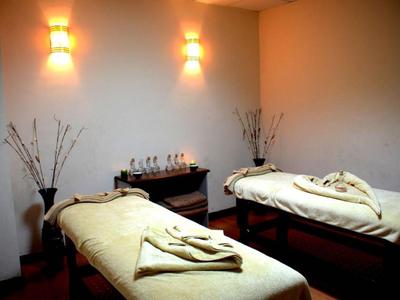 Zwei Massageliegen mit Handtüchern in einem warm beleuchteten Behandlungsraum.