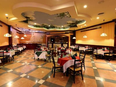 Elegantes Hotelrestaurant mit gedeckten Tischen, Stühlen und dekorativer Decke.