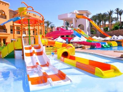 Bunte Wasserrutschen im Poolbereich eines sonnigen Ferienresorts mit Palmen.