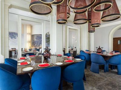 Elegancka jadalnia z niebieskimi krzesłami i okrągłymi drewnianymi stołami, idealna dla hotelu lub restauracji.