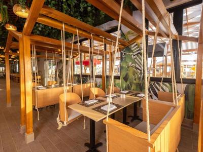 Przytulne nowoczesne miejsca do siedzenia z drewnianymi huśtawkami i tapicerowanymi ławkami w hotelowej restauracji.